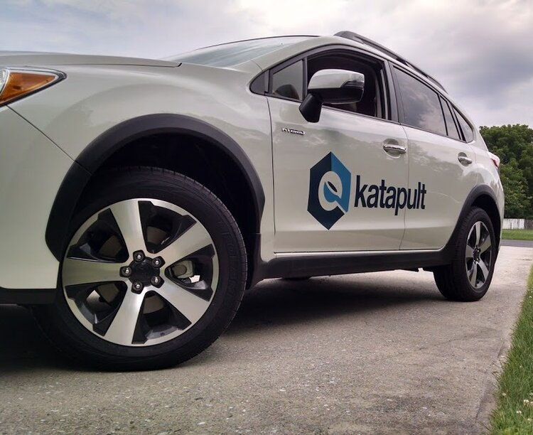 A white SUV with the Katapult logo on the side. 