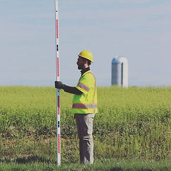 man holds measuring stick in a field 